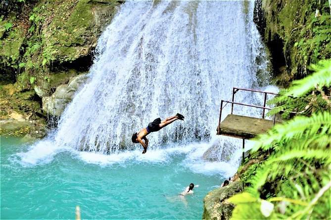 Tourist mid-jump into Blue Hole with vibrant surroundings 