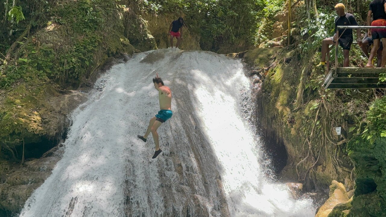 A tourist jumping off a cliff into Blue Hole's turquoise pool in Ocho Rios, Jamaica