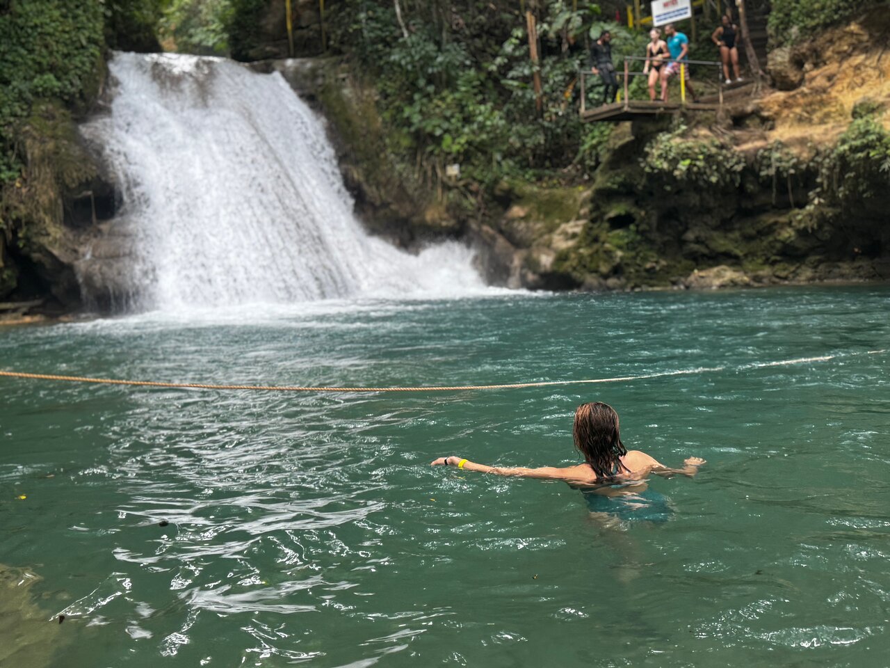 Tourist taking a swim in the vibrant blue lagoons of Blue Hole Secret Falls in Jamaica