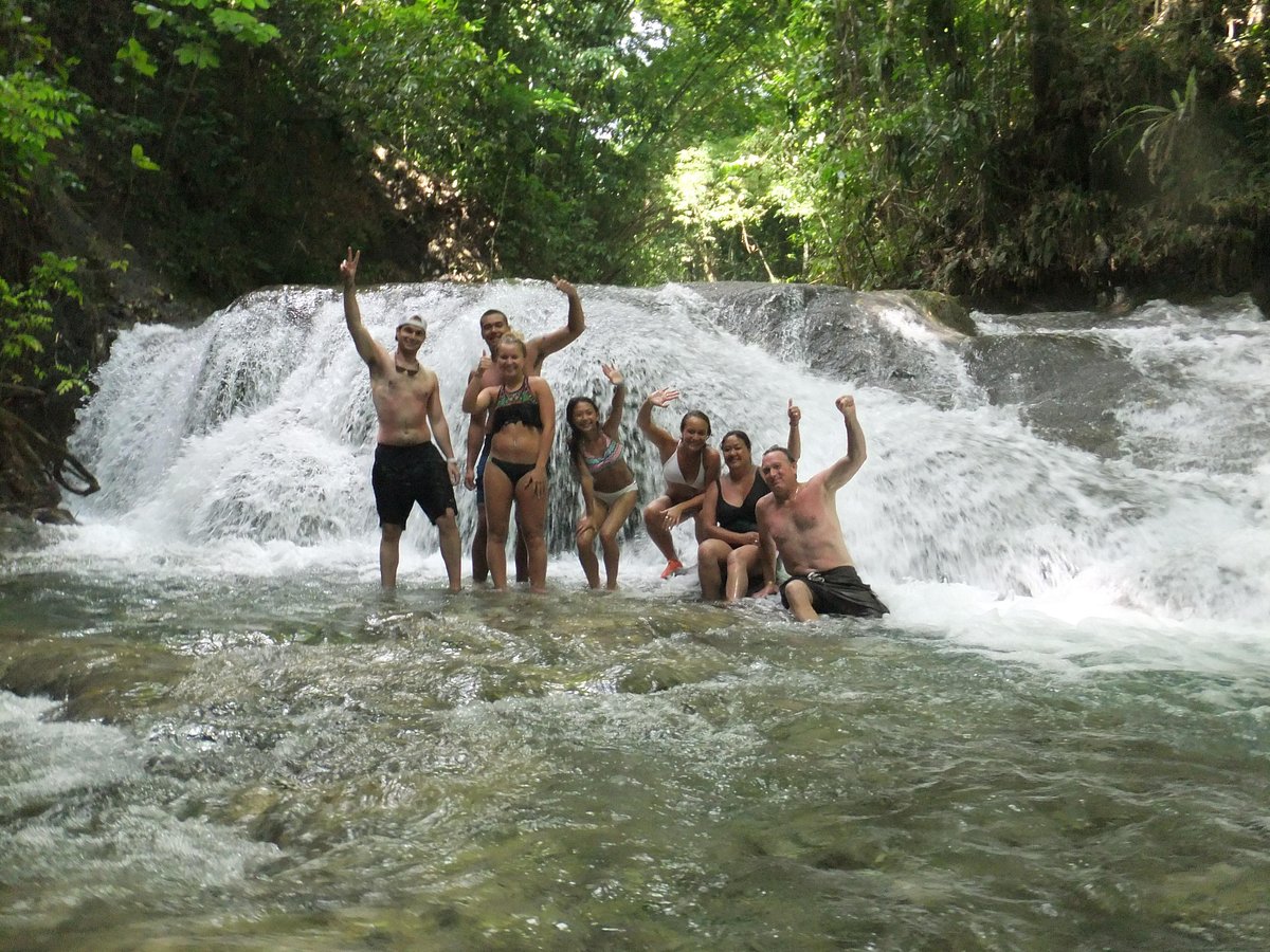 Tourists climbing Dunn's River Falls with guided safety measures.